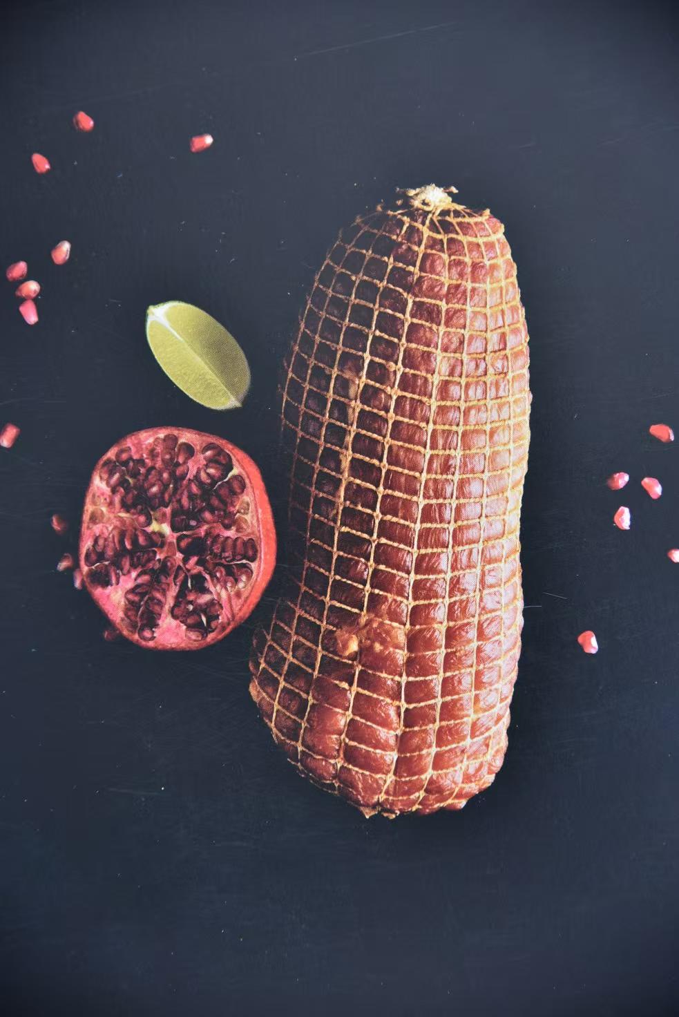 A netted roast displayed with pomegranate and lime