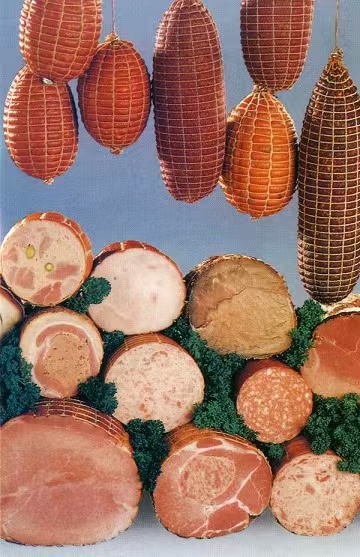 Assorted hams and salamis hanging in elastic netting