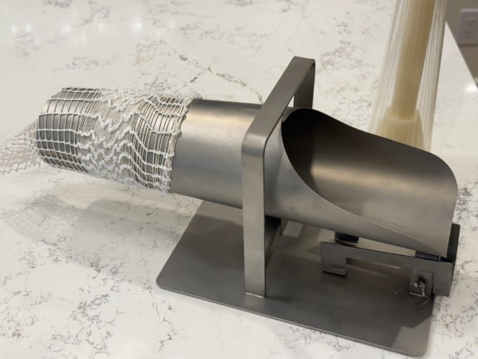 Manual stainless-steel netting applicator with white elastic netting shirred onto the tube